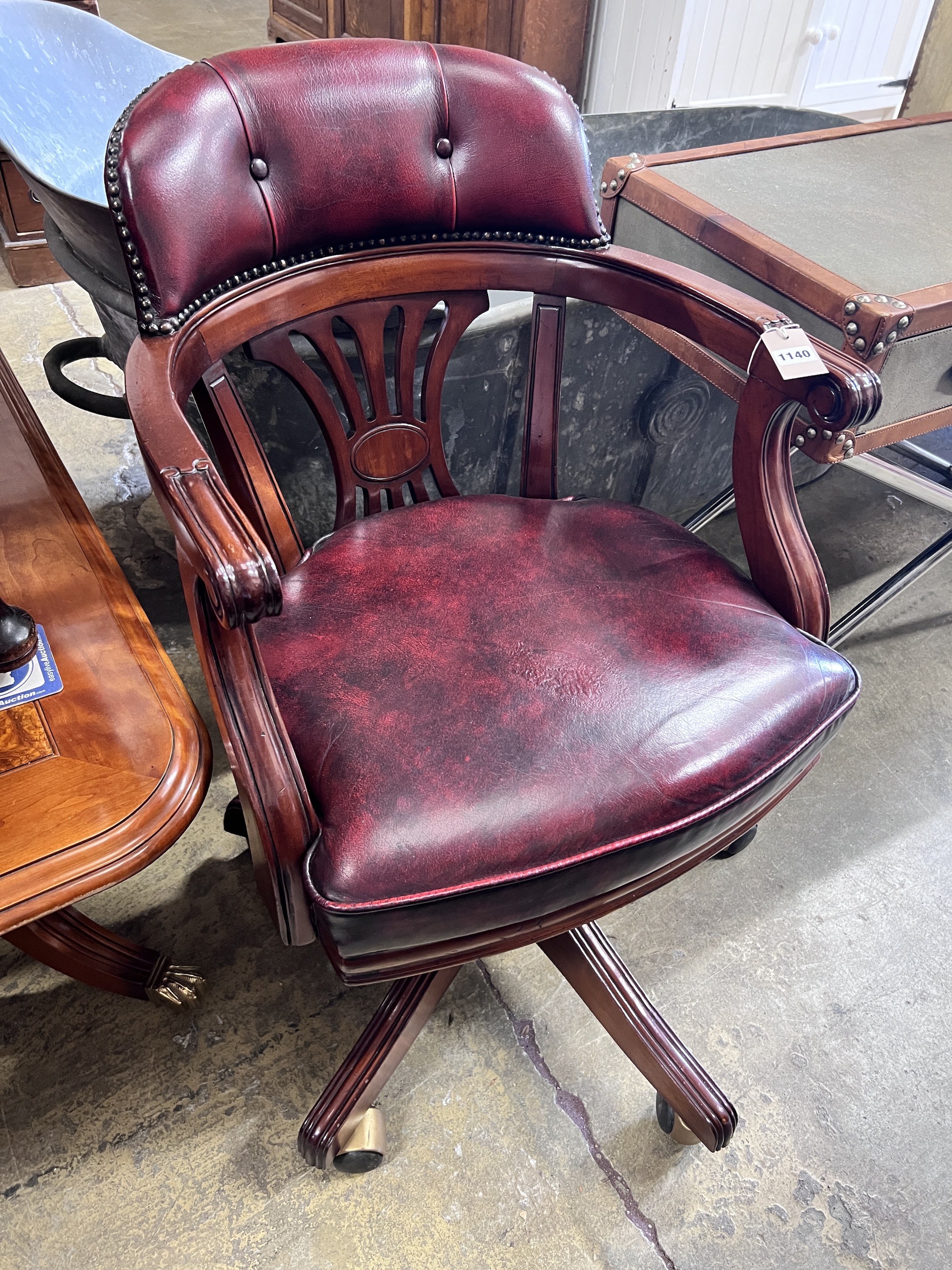 A modern mahogany revolving desk chair with leatherette upholstery, width 54cm